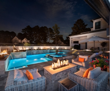night view of outdoor fireplace with pool in background