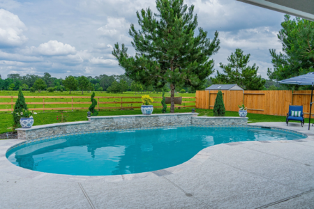 Cyan pool bordering a large field with trees
