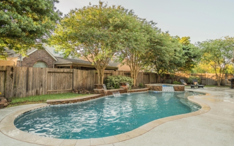 Evening view of a pool in a backyard shaded by trees