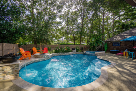 Orange chairs near a pool with fountains and spa