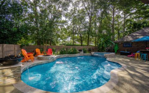 Orange chairs near a pool with fountains and spa